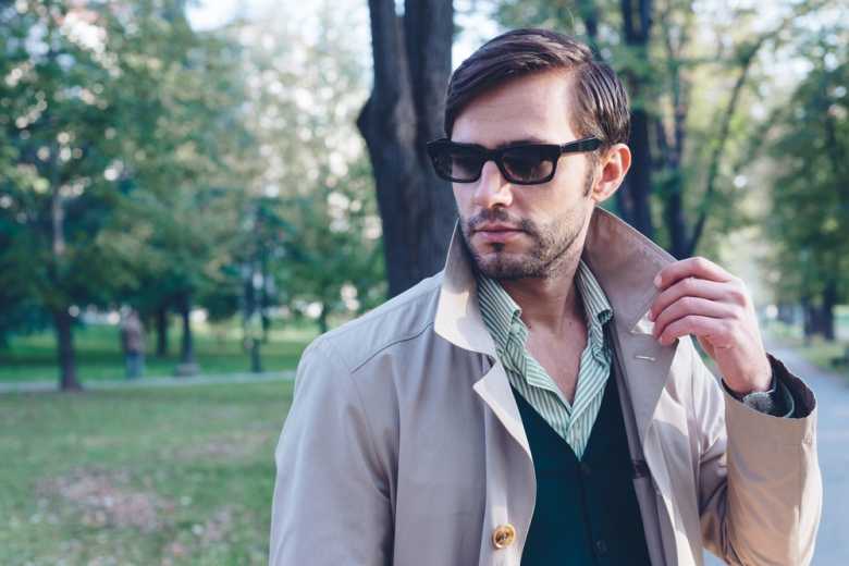 A man posing with a beige trench coat