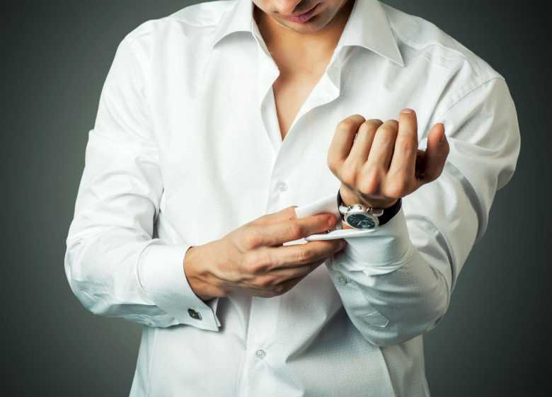 a man buttoning cuff of his shirt