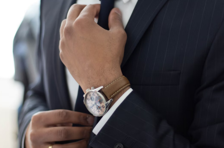 a close up of a man wearing a watch with a black suit