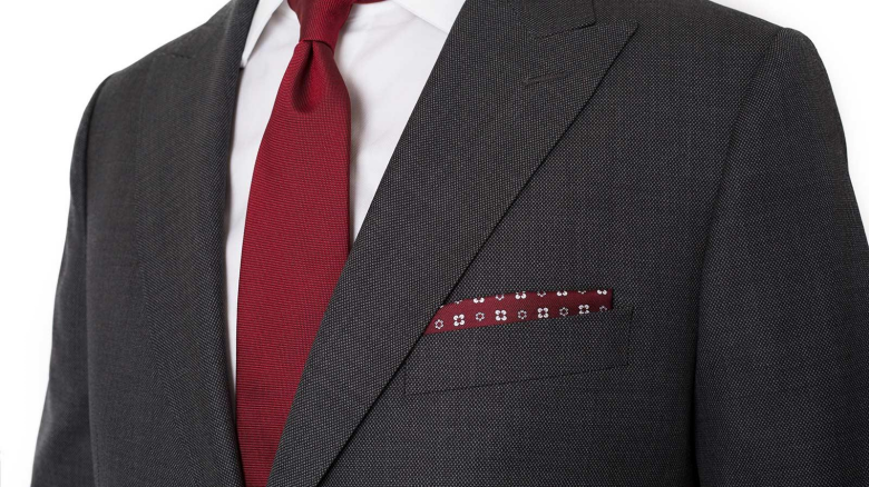 A close-up shot of a suit's jacket, combined with a red tie and a red handkerchief