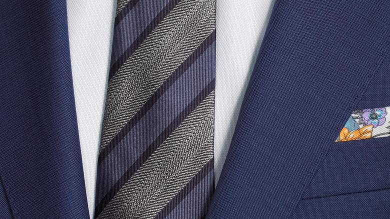 A close-up shot of a patterned tie in combination with a white shirt and a blue suit jacket